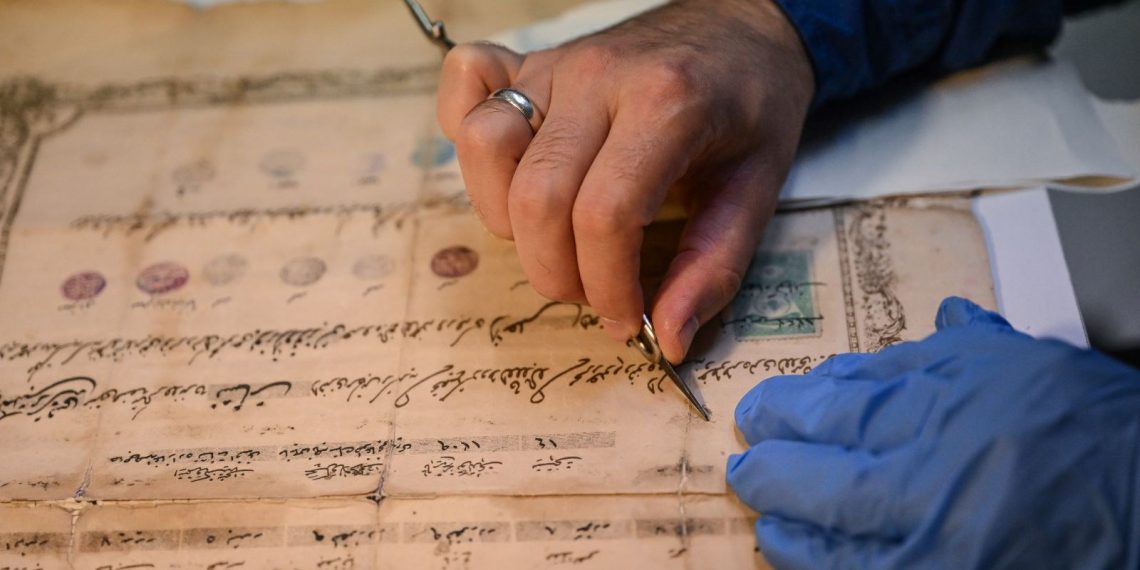 Atölyesinde eski evrak ve kitapları onarıp yeniliyor